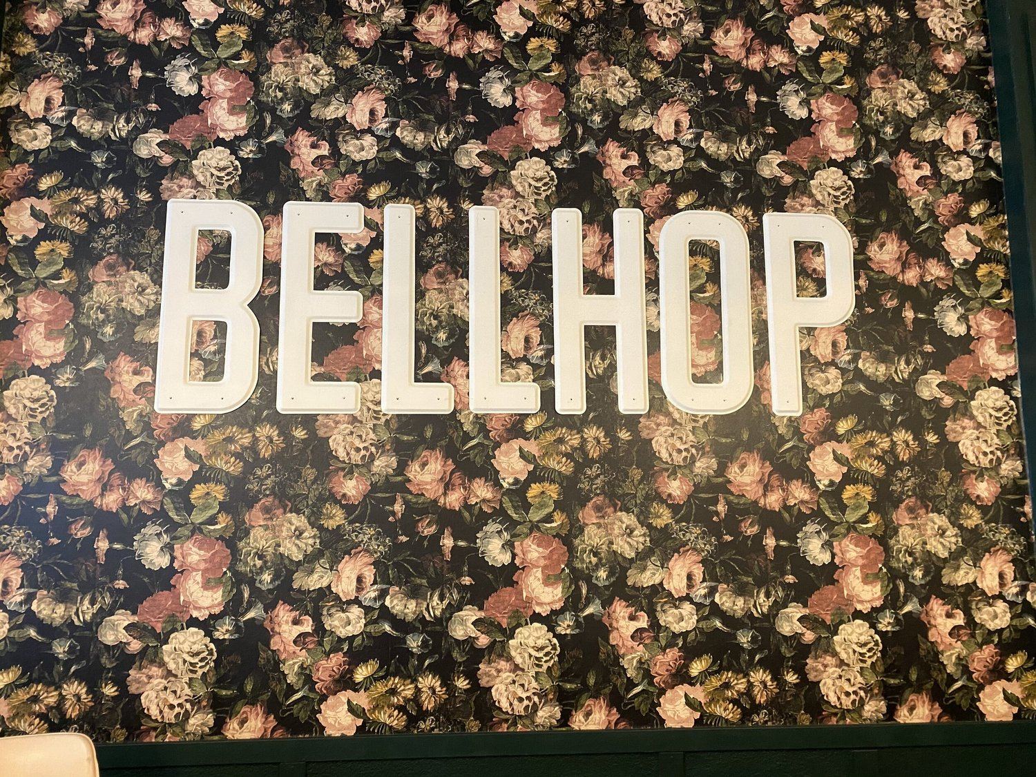 The BELLHOP letters on the dark floral wallpaper inside the dining room